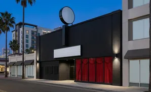 A modern building with a black facade, red curtains, and a blank marquee sign.