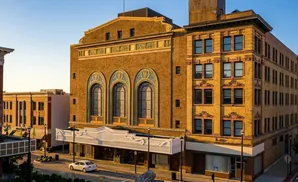 Ornate yellow brick building with arched windows, a white marquee, and a classic facade, bathed in golden hour light.