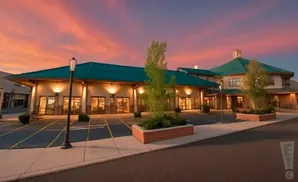 A building with a teal roof at sunset with orange and pink clouds.