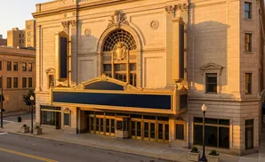 Golden hour light on an ornate theater facade with a marquee and large glass doors.