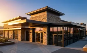 Modern building with stone accents and large glass windows at sunset.