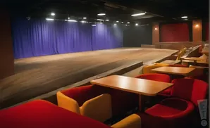 A stage with blue curtains and tiered seating in a theater.
