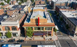 Aerial view of a downtown street with brick buildings, cars, and a bus.