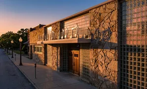 Building with stone facade and glass block windows, decorated with musical notes, at sunset.
