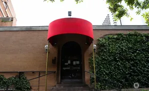 Red awning over a brick building entrance with ivy-covered walls.