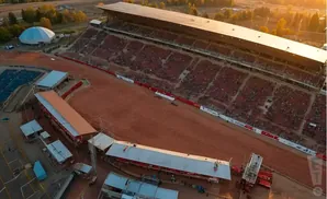 Aerial view of a rodeo arena with stadium seating and a large domed building.