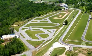Aerial view of a winding race track surrounded by green trees and grass.