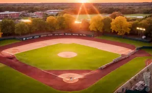 An aerial view of a baseball field at sunset, with players on the field.