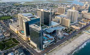 Aerial view of a coastal city with casinos, a Ferris wheel, and a beach.