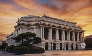 Neoclassical building with columns and arched windows against a vibrant sunset sky.