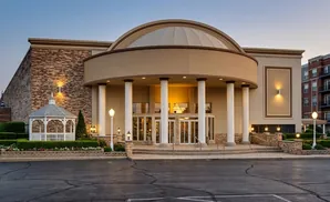 Exterior of a domed building with brick accents, columns, and a white gazebo.