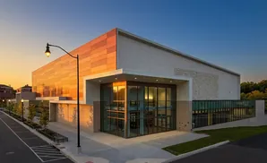 Modern building with orange facade and glass entrance at sunset.