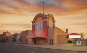 Marquee theater with arched facade against a vibrant sunset sky.