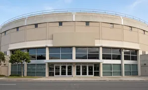 A circular, tan building with a concrete rim and large windows.