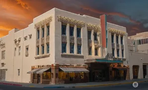 An old movie theater with a decorative facade and marquee, under a dramatic orange sky.