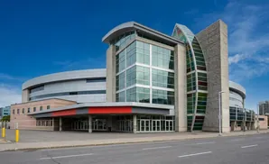 Modern building with a curved silver roof, large glass windows, and stained glass accents under a blue sky.