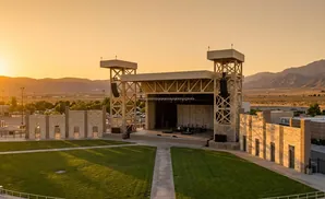 An outdoor amphitheater stage at sunset with mountains in the background.