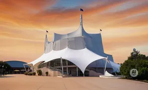 A white tent-like building with flags under an orange sunset sky.