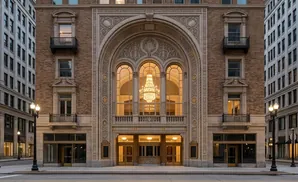 Ornate building facade with arched windows, a chandelier, and decorative stonework.