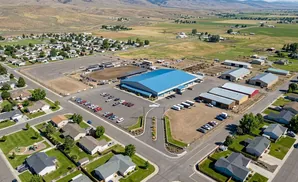 Aerial view of a community with a large blue building, rodeo arena, housing, and agricultural facilities.