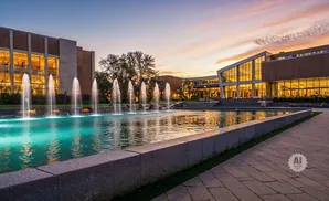 A modern building with large windows and fountains at dusk.