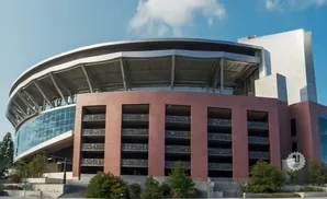 A large stadium with a curved glass facade and red brick structure on a sunny day.