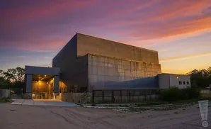 A concrete building under a dramatic pink and orange sunset sky.