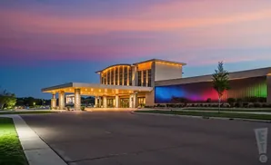 Modern building exterior at dusk with colorful lights and a pink and blue sky.