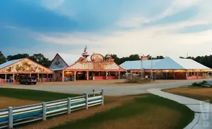 Amusement park buildings with tents and colorful trim under a cloudy sky.