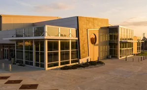 Modern building with large windows and tan brick facade illuminated by golden hour light.