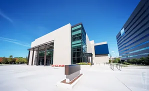 Modern building with glass facade and a blue screen, next to a tall striped building.