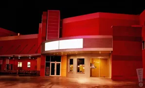 A modern movie theater facade at night, bathed in red light.