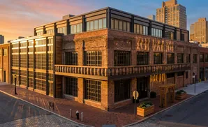 A brick building with large windows and a balcony at sunset.