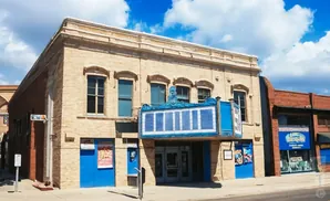 A vintage theater with a marquee and blue doors stands on a sunny day.