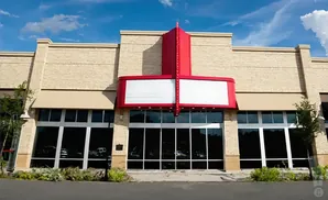 A beige brick building with a red and white marquee above large glass windows.