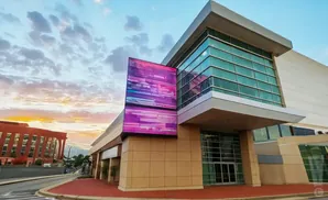 Modern building with large glass windows and a colorful LED display screen outside.