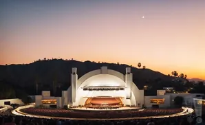 Hollywood Bowl at dusk with an orchestra performing on stage and a crowd in the audience.