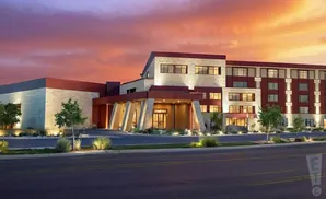 A modern hotel with stone and maroon accents at sunset.