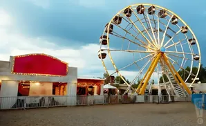 Ferris wheel and carnival games under a cloudy sky.