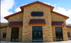 A stone building with a red roof and large glass doors.