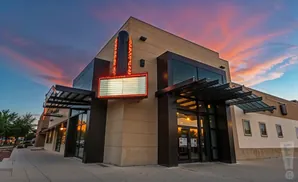 Modern building with a marquee sign against a sunset sky.