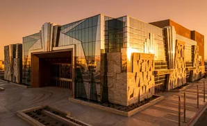 Modern building with glass facade and stone accents reflecting sunset.