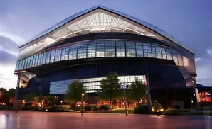 Modern stadium at dusk with glass facade and illuminated interior.