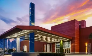 Modern red building with a tall blue tower and colorful sunset sky.
