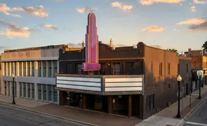 Art Deco theater with a purple neon marquee at sunset.