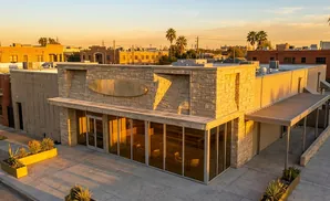 Modern storefront with stone facade and large windows, bathed in golden sunset light.