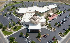 Aerial view of a hotel with a large Native American pot sculpture on the roof, surrounded by parking lots and landscaping.