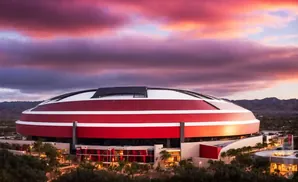 A futuristic red and white stadium under a dramatic purple and pink sunset sky.