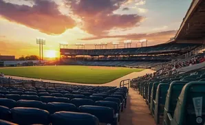 A baseball stadium at sunset, with a vibrant sky over the field and empty seats in the foreground.
