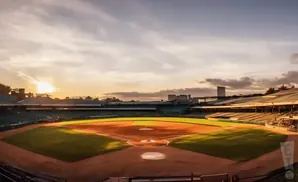 Baseball stadium at sunset with the sun setting behind the outfield bleachers.